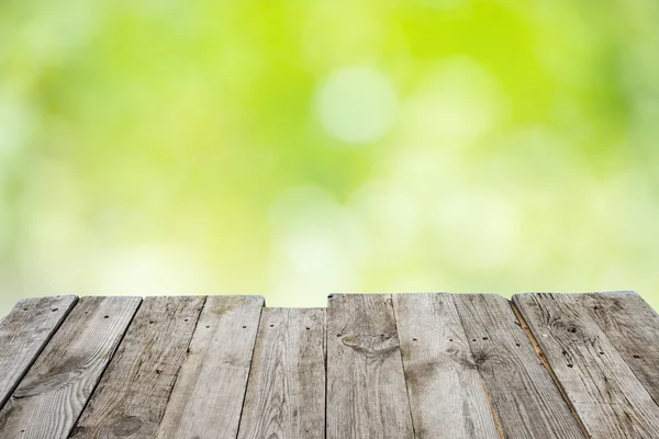 Prázdné dřevěný stůl s listy bokeh — Stock fotografie