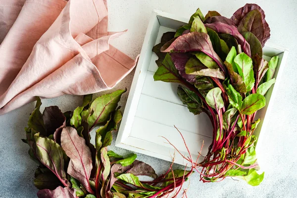 Fresh raw beetroot leaves as a healthy cooking concept on stone background with copy space