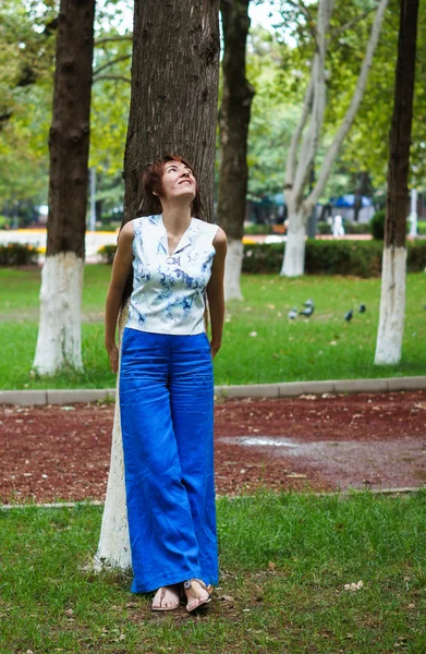 Agradable mujer de pie junto a un árbol — Foto de Stock