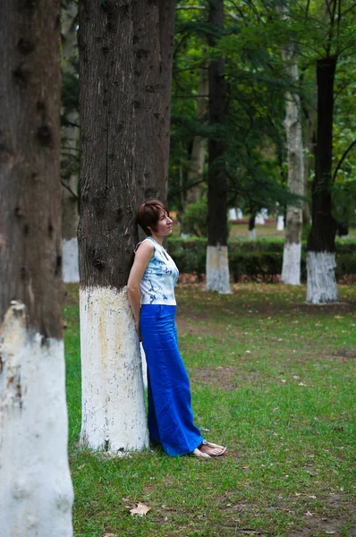 Agradable mujer de pie junto a un árbol — Foto de Stock