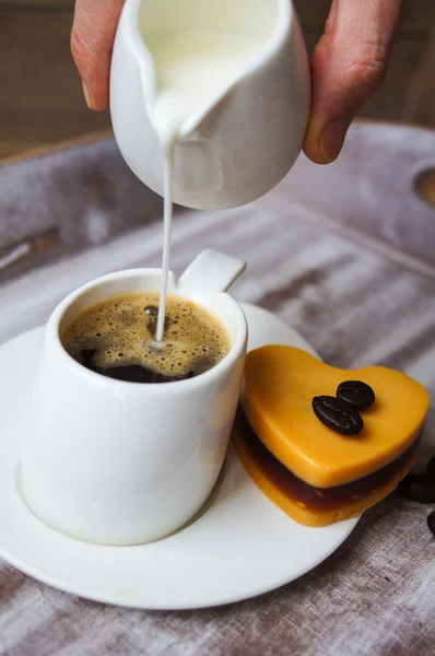 Alguien añade leche al café negro — Foto de Stock