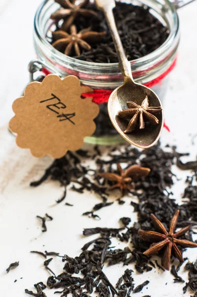Feuilles de thé noir sur fond rustique — Photo
