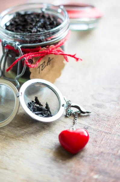 Black tea leaves in the jar with note on rustic background — Stock Photo, Image