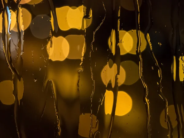 Gotas de lluvia en el cristal de una ventana por la noche — Foto de Stock