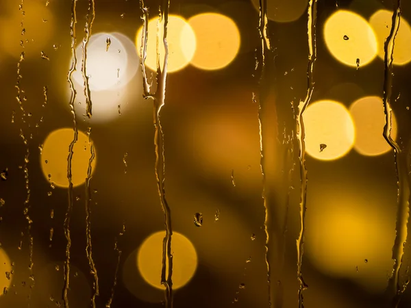 Gotas de lluvia en el cristal de una ventana por la noche — Foto de Stock