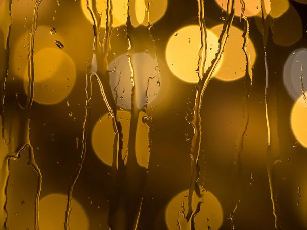 Gotas de lluvia en el cristal de una ventana por la noche —  Fotos de Stock