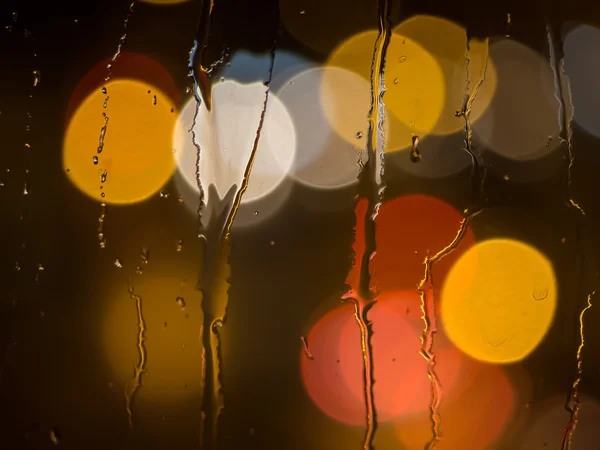 Gotas de lluvia en el cristal de una ventana por la noche — Foto de Stock