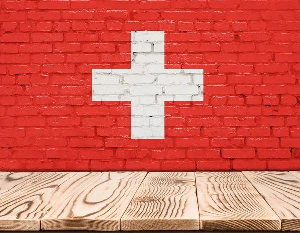 Bandera de Suiza pintada sobre pared de ladrillo con suelo de madera —  Fotos de Stock