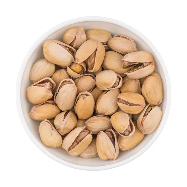 At the center of the frame white bowl with pistachio nuts on a w — Stock Photo, Image