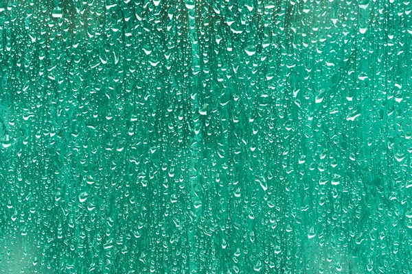 Water drops on glass on green background — Stock Photo, Image