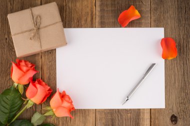 Boş defter, kalem bir gül ve ahşap bir masa üzerinde bir hediye
