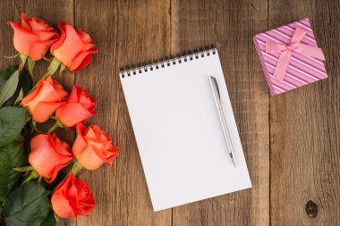 Boş defter, kalem bir gül ve ahşap bir masa üzerinde bir hediye