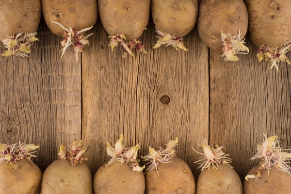 Batatas germinadas para plantio em uma superfície de madeira — Fotografia de Stock