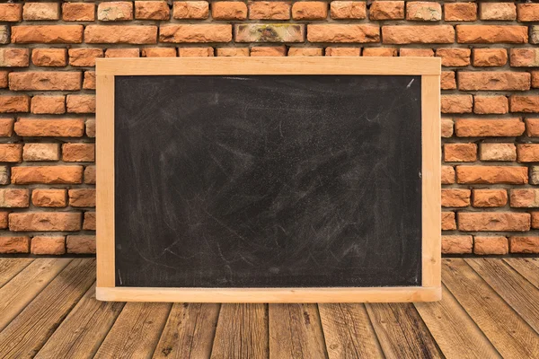 Leeg schoolbord op diagonale houten tafel in rode bakstenen muur, Temp — Stockfoto