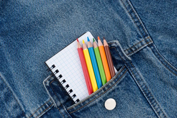 Pocket denim jacket with a notebook and colored pencils. Top vie — Stock Photo, Image