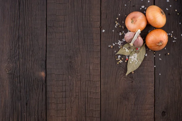 Zwiebeln, Knoblauch und Gewürze auf einem alten Holztisch. — Stockfoto