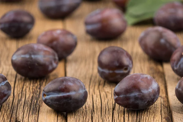 Ameixas frescas em uma mesa de madeira escura . — Fotografia de Stock