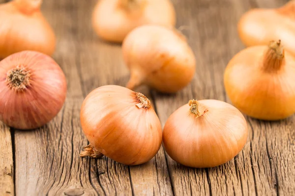 Onions on old wooden table. — Stock Photo, Image