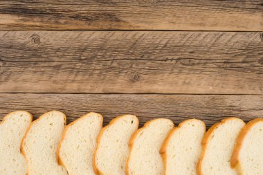 Eski bir ahşap masada ekmek dilimlenmiş.