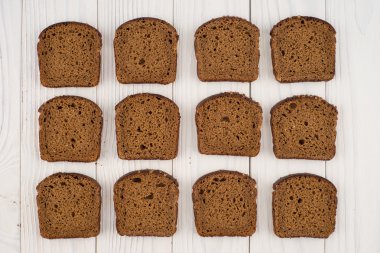 Eski bir beyaz tahta masada kahverengi ekmek dilimlenmiş. 