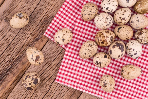 Quail eggs on a red napkin on old wooden table. — Stock Photo, Image