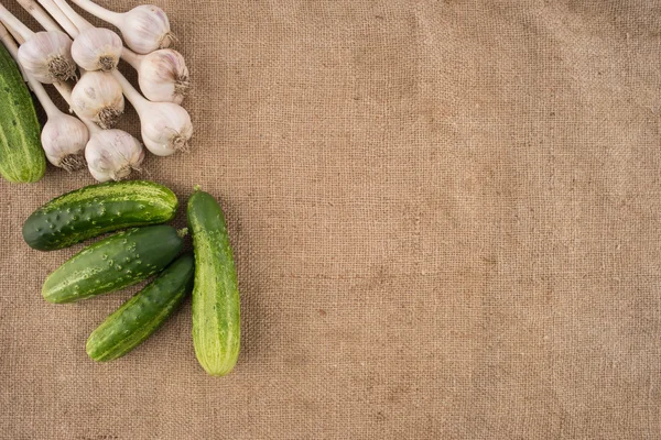 Cucumbers and garlic on a sacking — Stock Photo, Image