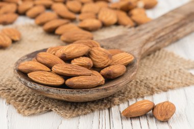 Eski beyaz tahta masada bir tahta kaşık badem.