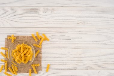 Eski ahşap masa üzerinde bir cam kapta makarna.