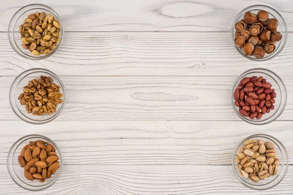 Mélanger les noix dans un bol en verre sur la vieille table en bois . — Photo