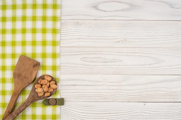 Frijoles en una cuchara de madera sobre una vieja mesa de madera . — Foto de Stock