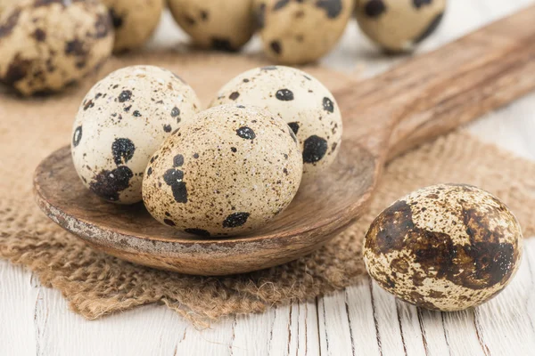 Quail eggs in a wooden spoon and an old wooden table. — Stock Photo, Image