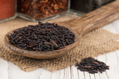 Siyah eski ahşap masa üzerinde bir tahta kaşık pirinç.