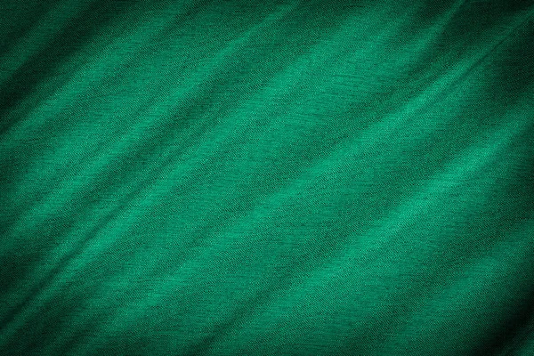 green background of fabric from a piece of crumpled clothes. Top view.