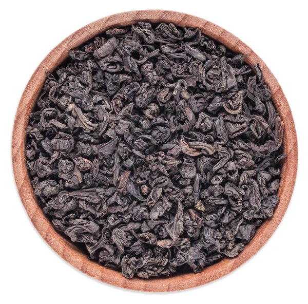 Trockener schwarzer Tee in einer hölzernen Schüssel auf weißem Hintergrund — Stockfoto