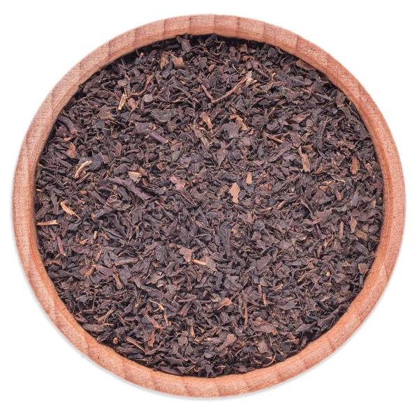 Сухой черный чай в деревянной чашке на белом фоне — стоковое фото