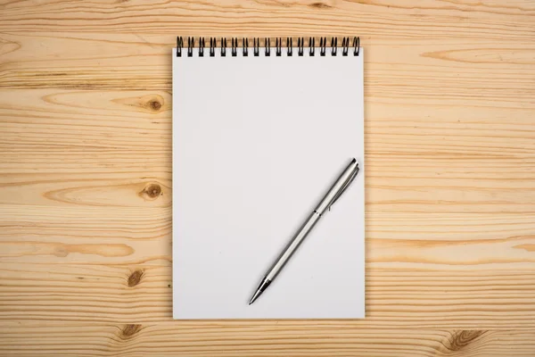 Blank notepad with pen on office wooden table