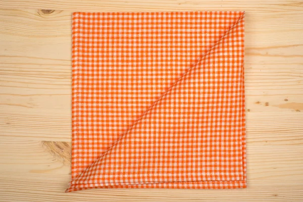 Складная оранжево-белая салфетка на деревянном столе — стоковое фото
