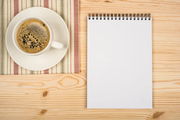 Notebook and cup of coffee in wood table — Stock Photo, Image