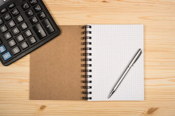 Notebook, ballpen and calculator on wooden desk — Stock Photo, Image