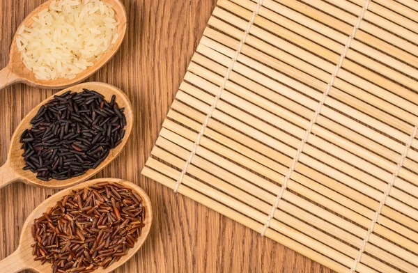 Roter, weißer und schwarzer Reis in einem Holzlöffel auf einem Holztisch — Stockfoto