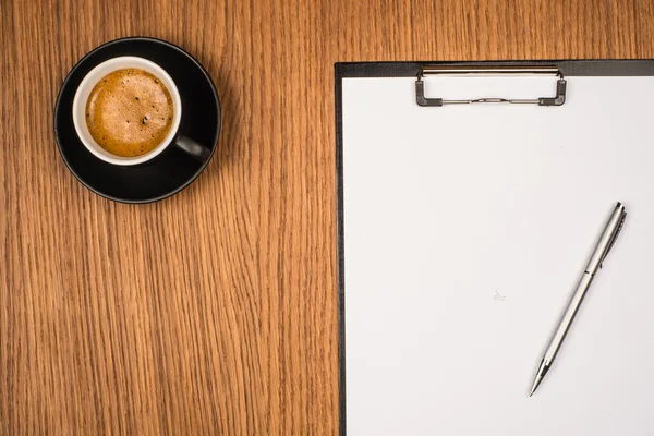 Clipboard with blank page and cup of coffee on wooden desk. View — Stock Photo, Image