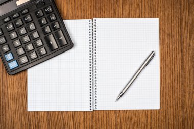 defter, ballpen ve ahşap masa hesap makinesi