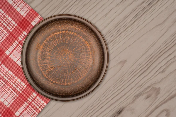 Бурая глиняная тарелка на столе — стоковое фото