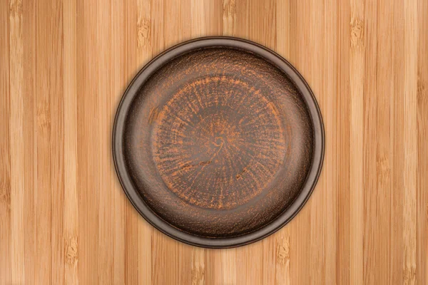 Empty brown ceramic plate on rustic wooden background — Stock Photo, Image