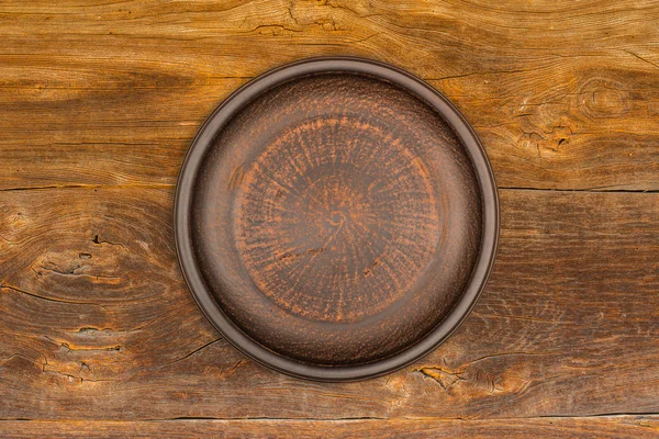 Rustik ahşap zemin üzerinde boş kahverengi seramik tabak — Stok fotoğraf