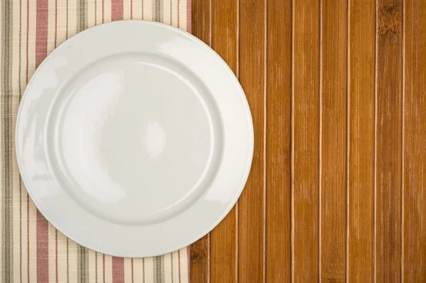 Empty white plate on wooden table — Stock Photo, Image