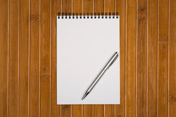 Bloc de notas en blanco con pluma en la mesa de madera de la oficina — Foto de Stock
