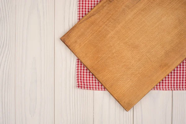 Empty kitchen cutting board. Wooden table covered with red check — Stock Photo, Image