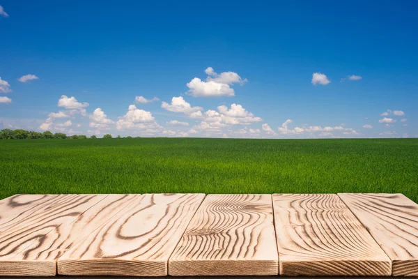 Mesa de deck de madeira sobre belo prado com céu azul — Fotografia de Stock