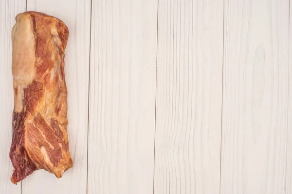 Räucherfleisch auf einem weißen Holztisch. — Stockfoto